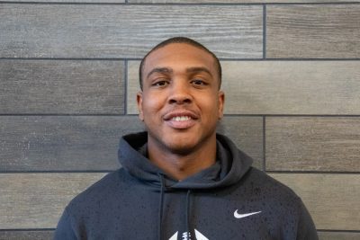 A photo of Christopher Anderson standing in front of a gray slate tile wall.