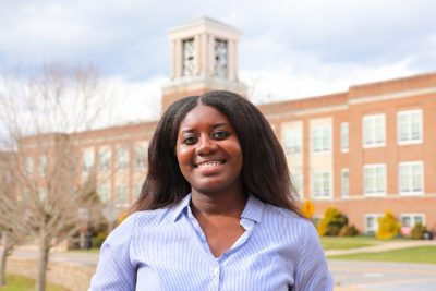 A photo of Amma Osei-Boakye with Concord's bell tower in the backdrop.